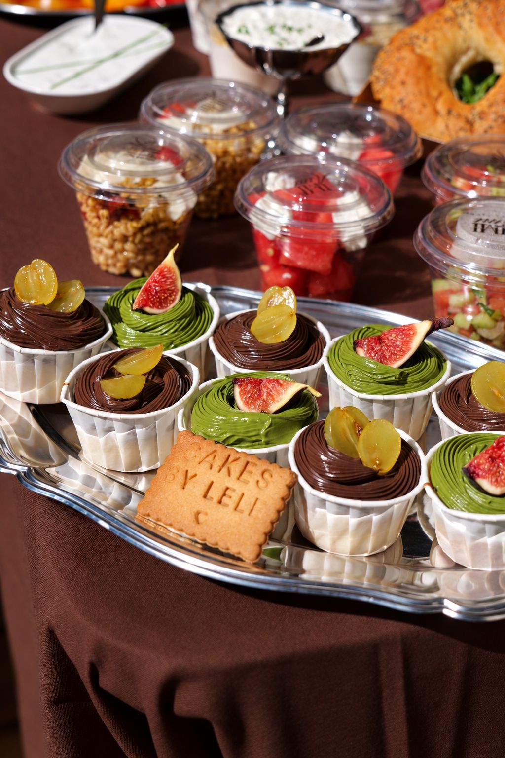Cupcakes matcha et chocolat surmontés de figues fraîches sur un plateau argenté.